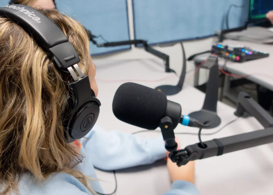 Close up of student using podcast microphone.