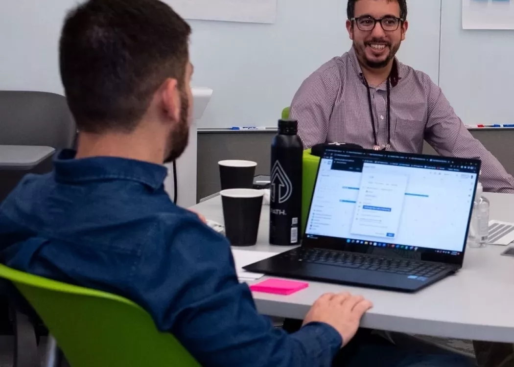 People sitting at a table with laptops in the TILL