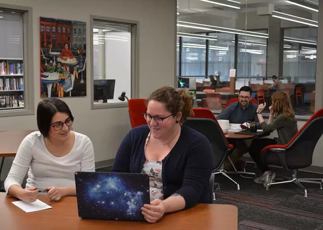 People working together at tables in the Across Disciplines Writing Center Workshop