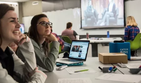 Students at table watching a video on screens in the TILL classroom